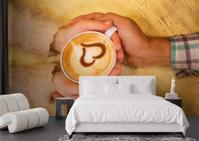 Four hands wrapped around a cup of coffee with heart drawing Wall mural