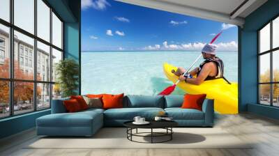 Young caucasian man kayaking in sea at Maldives Wall mural