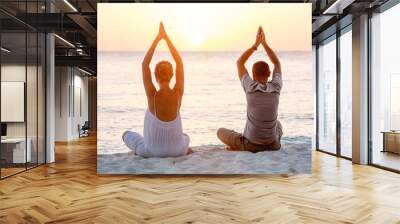 young couple sitting on the beach of the sea in the lotus positi Wall mural