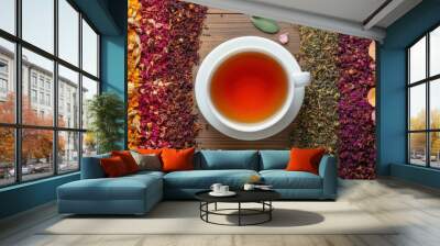 Cup of tea with assorted tea blends on wooden surface. Wall mural