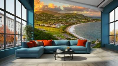 Panorama of Saint Kitts and its capital Basseterre during sunset, beautiful green mountains and a beach in paradise caribbean island with amazing green and orange colors. Saint kitts and nevis Wall mural