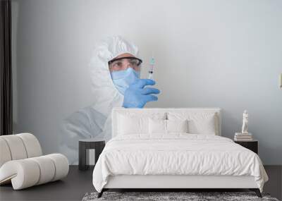 fully sheltered doctor holding syringe in hand. Young doctor preparing for vaccination. find the vaccine Wall mural