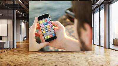 man using his mobile phone on the coast Wall mural