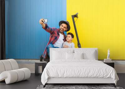 Young Father Taking a Selfie with his Son on an Electric Scooter. Wall mural