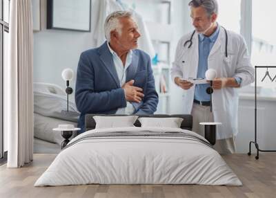 A doctor is examining an elderly man with stomach pain in the medical room, holding his belly. Portrait of senior man sharing health issues struggles with his medical professional carer practitioner Wall mural