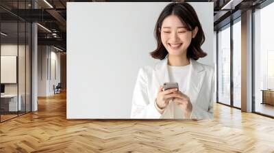 A smiling Japanese business woman holding her smartphone. asian businesswoman on white background Wall mural