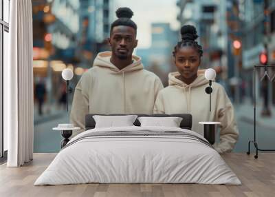 Photo of an attractive young black man and woman wearing plain cream colored hoodies Wall mural