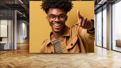 Positive man in denim outfit points to camera. Brunette dark-skinned guy Wall mural