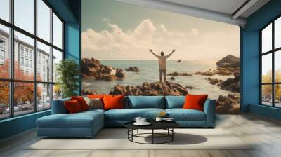 Successful man with arms up on the beach with his arms up showing the ocean raising hands to the sky. Wall mural