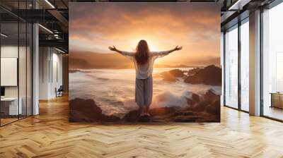 Successful woman with arms up on the beach with his arms up showing the ocean raising hands to the sky. Wall mural