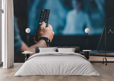 hand holding remote to press button to turn on or off television at home concept. person using remote control tv to select and change channel of movie to news. remote of smart tv is new technology Wall mural