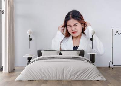 A frustrated and irritated young woman pulling her hair with both hands in annoyance. Isolated on a white background. Wall mural