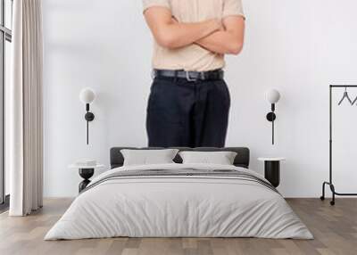 Portrait of a confident young Asian man standing with arms crossed, dressed in casual attire on a white background. Wall mural