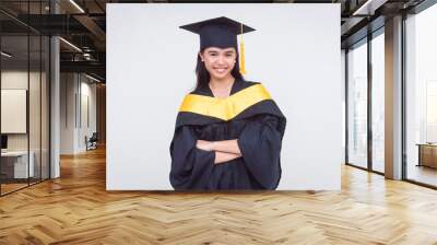 Portrait of a young college graduate in cap and gown, smiling arms crossed, isolated on a white background. Wall mural