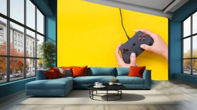 Hands Holding Gamepad. Black joysticks on yellow background. Computer game competition. Gaming concept. Place for text. Flat lay, top view, copy space. Wall mural