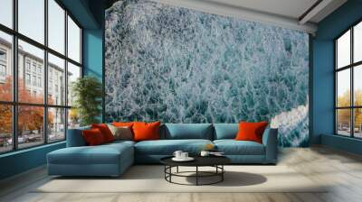 Drone photo of The dramatic lapping of the waves in the ocean produces white foam. The sea water of the pond is blue and contrasts with the color of the foam Wall mural