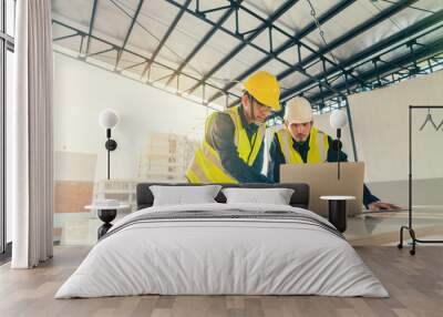 Asian man Civil Engineer and Contractor working with computer laptop on the table in construction site. Architect and Builder with computer laptop discussion planning on progress together. Wall mural