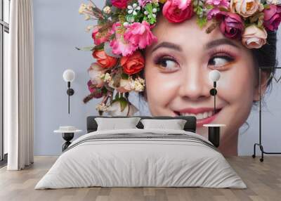 Close up of beautiful young asian woman smiling with flowers on her head. Brunette woman with luxury makeup. Perfect skin. Eyelashes. Cosmetic eyeshadow. Wall mural