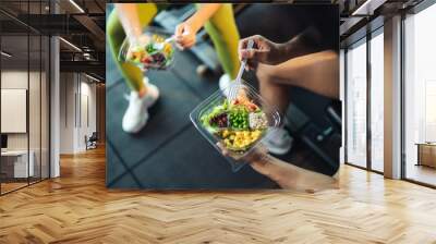 Top view Asian man and woman healthy eating salad after exercise at fitness gym. Two athlete eating salad for health together. Selective focus on salad bowl on hand. Wall mural