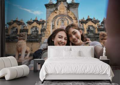 Two Asian woman traveler smile take a photo selfie together with pagoda of buddhist temple in background. Travel pagoda of buddhist in Asia. Wall mural