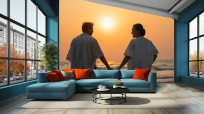 Elderly couple moments of relaxation with a happy picture impression. Tour. Portrait of a middle-aged man standing holding hands by the sea in the evening. Wall mural