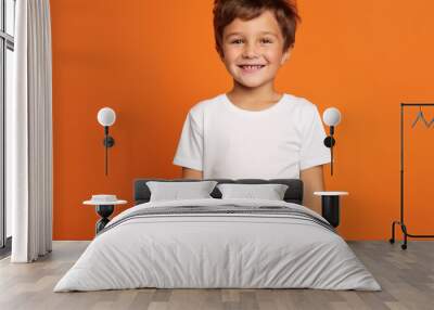 A portrait shot of a little kid wearing a white t-shirt with orange background Wall mural