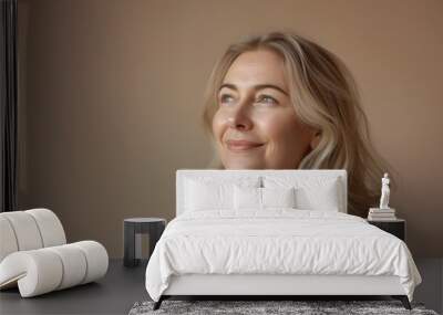 Portrait of a confident mature woman looking up and over with a slight smile against an earthy background Wall mural