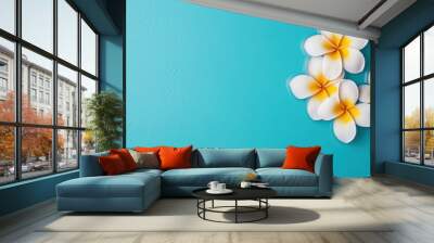 White and yellow frangipani flowers on a blue background, showcasing tropical beauty and summer blooms Wall mural