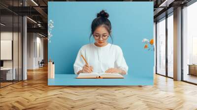 Young asian woman in white shirt writing down her aspirations and positive affirmations for the year in a journal, Self-reflection, Goal setting,school background Wall mural