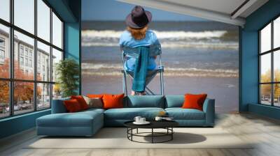 Woman sitting on the beach enjoying the sea view. Wall mural