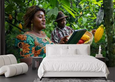 On a cocoa plantation, two farmers carry out quality control with a tablet before the harvest Wall mural