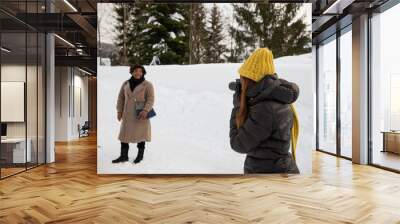 Professional photographer takes a photo of a lady in the mountains in a snowy landscape. Wall mural