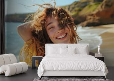 Carefree woman with wavy hair posing joyfully by the seaside beach, Generative AI Wall mural