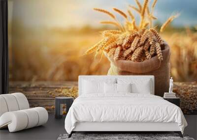 A bag of wheat is sitting on a wooden table. The scene has a rustic, natural feel to it, with the wheat representing the bounty of the harvest season Wall mural