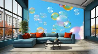 A bunch of colorful bubbles floating in the sky. The bubbles are of different colors and sizes, creating a vibrant and playful atmosphere. The blue sky serves as a backdrop, emphasizing the bright Wall mural