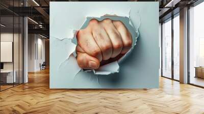 A fist is shown through a hole in a wall. The fist is clenched and the hand is extended. Concept of strength and power Wall mural