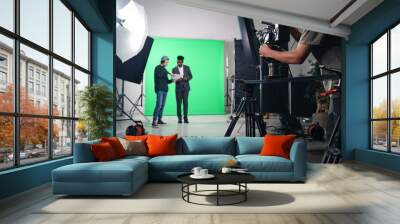 Cameraman shooting TV program on professional camera in studio Wall mural