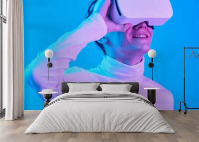 Man wearing virtual reality headset smiling and experiencing virtual world in a blue-lit room Wall mural