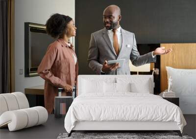 Portrait of luxury hotel manager welcoming young Black woman entering hotel room enjoying travel copy space Wall mural