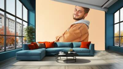 Waist up portrait of smiling young man looking over shoulder at camera in studio, copy space Wall mural