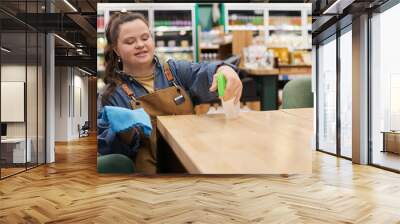 Waist up portrait of smiling young woman with disability working in supermarket and sanitizing tables in cafe area copy space Wall mural