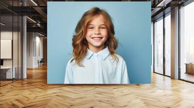 A young girl with long brown hair is smiling and wearing a blue shirt Wall mural