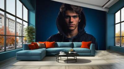 A young man is wearing a black hoodie and is looking directly at the camera Wall mural