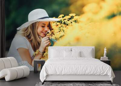 Beautiful young woman smelling yellow flower in the park. Wall mural