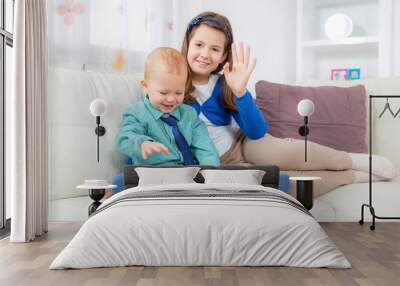 Brother and sister sitting in living room reading book Wall mural