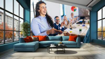 Businesswoman receiving award from businessman in front of business professionals, applauding at business seminar in office building Wall mural