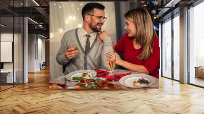 Couple drinking wine and laughing while sitting around a dining table during a dinner party Wall mural