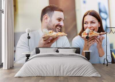 Couple eating pizza snack outdoors. Wall mural