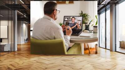 Deaf man talking using sign language on the laptop at home. Wall mural