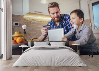 Father and son using digital tablet for online shopping at breakfast table Wall mural